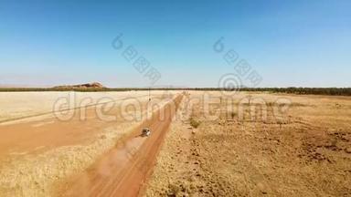 当无人驾驶飞机上升时，<strong>越野汽车</strong>沿着沙漠道路行驶的速度，揭示干旱的景观
